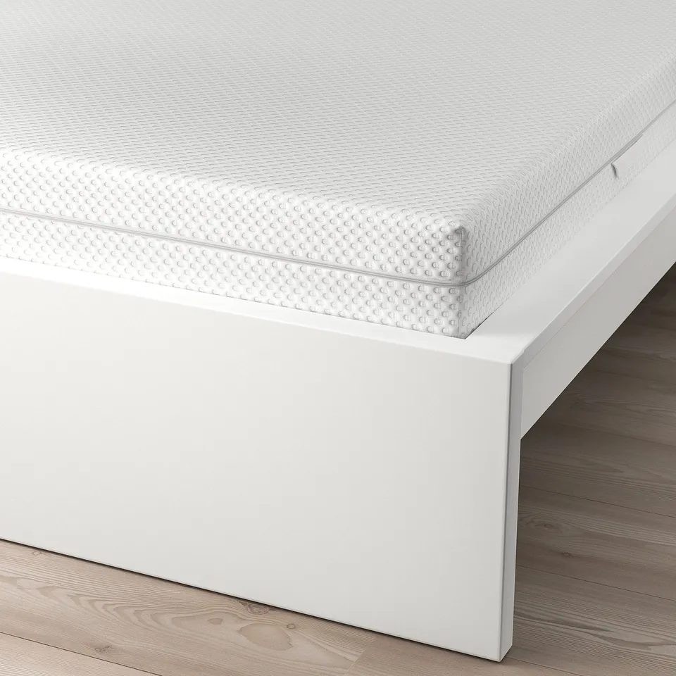 A minimalist bed with adjustable sides, supporting various mattress thicknesses, on a wooden floor.