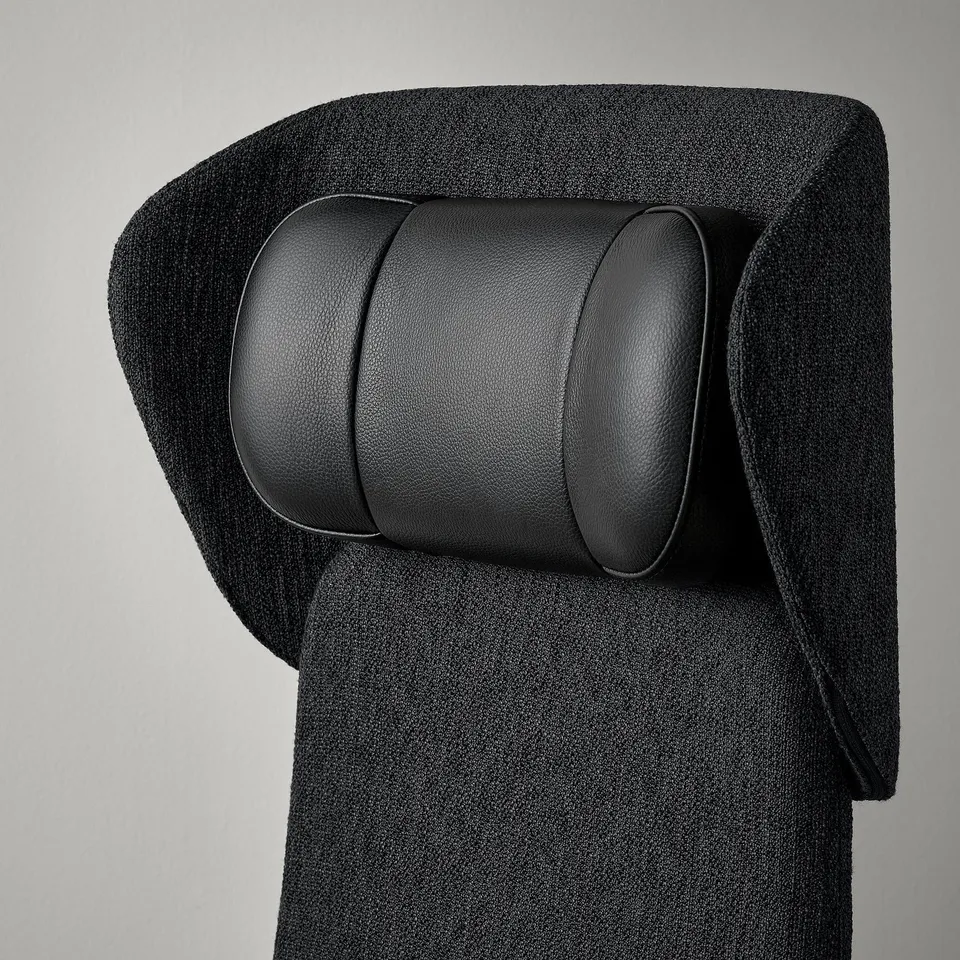 Black leather headrest on a grey fabric chair, showcasing high-quality materials and design.