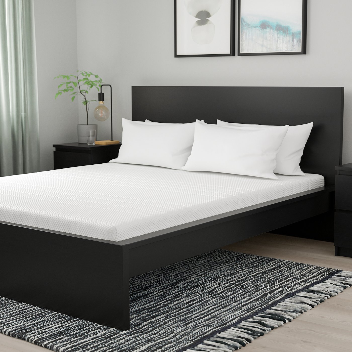Modern black bed with white bedding, bedside table with plant, and artwork in room.
