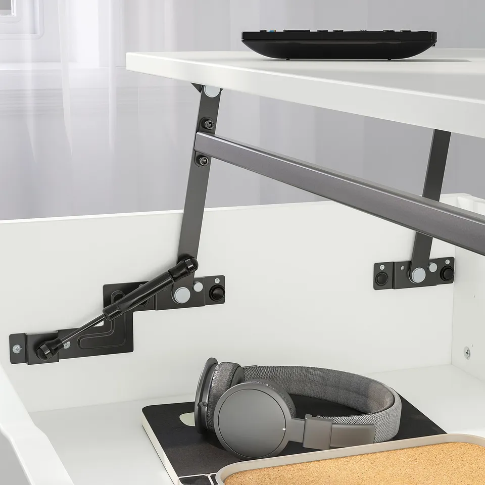 Adjustable coffee table with two heights, featuring a lifting mechanism and hidden storage. Headphones and keyboard are visible on the table.