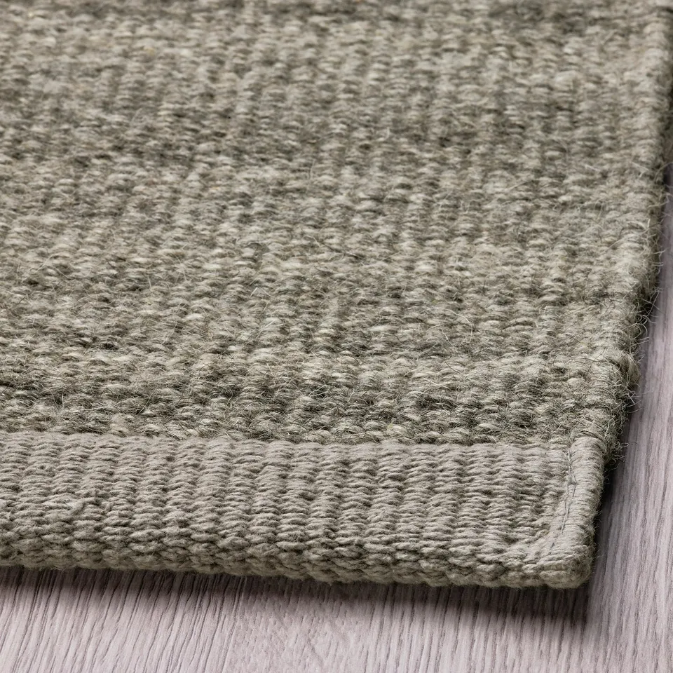 Flatwoven grey rug on floor, soft wool texture, elegant melange pattern, ideal for comfort and warmth.