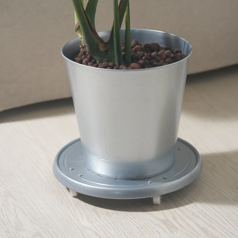 Metal plant tray with wheels holding a potted plant, designed for easy movement and floor protection.
