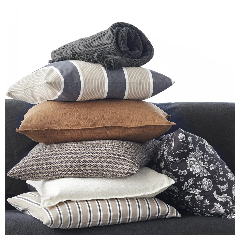 Cushions and blanket on couch, varied colours and patterns.