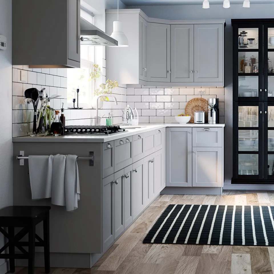 Modern kitchen with grey cabinets, white subway tiles, stainless steel appliances, black and white striped rug, under-cabinet MITTLED lighting.