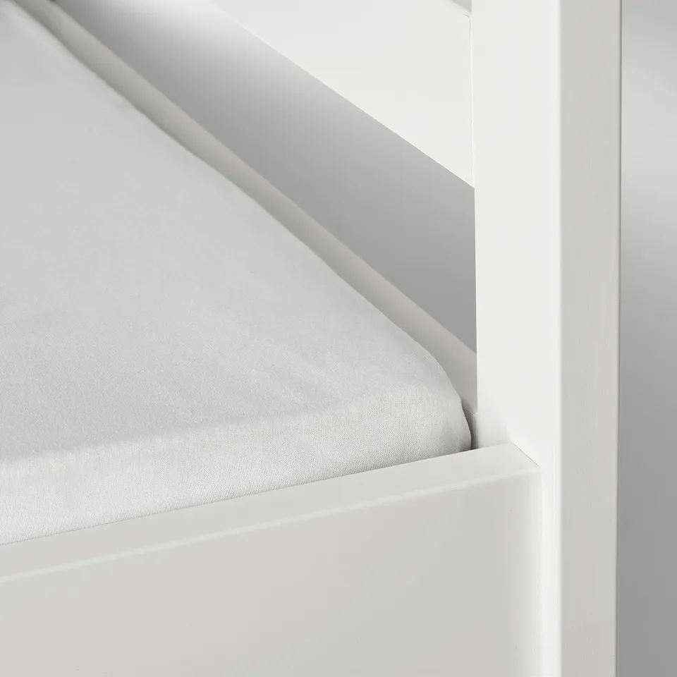 A fitted sheet with elastic keeping it taut on a mattress.