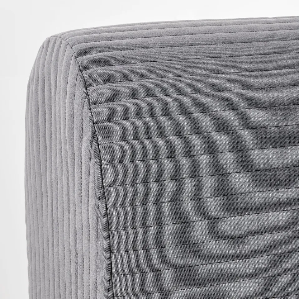 Close-up of a grey fabric sofa-bed with vertical lines, showcasing its plush, quilted texture and sturdy construction.
