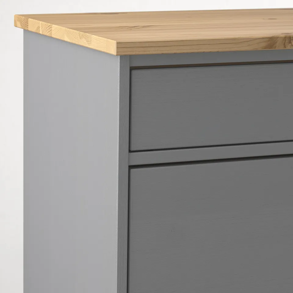 Close-up of KALLSÖ furniture corner, showing sleek grey drawers and natural wooden top.