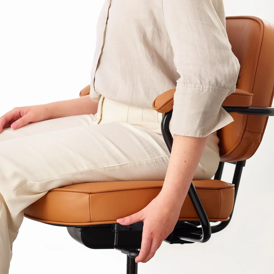 Person sitting in an ergonomic office chair with adjustable armrests and lumbar support.