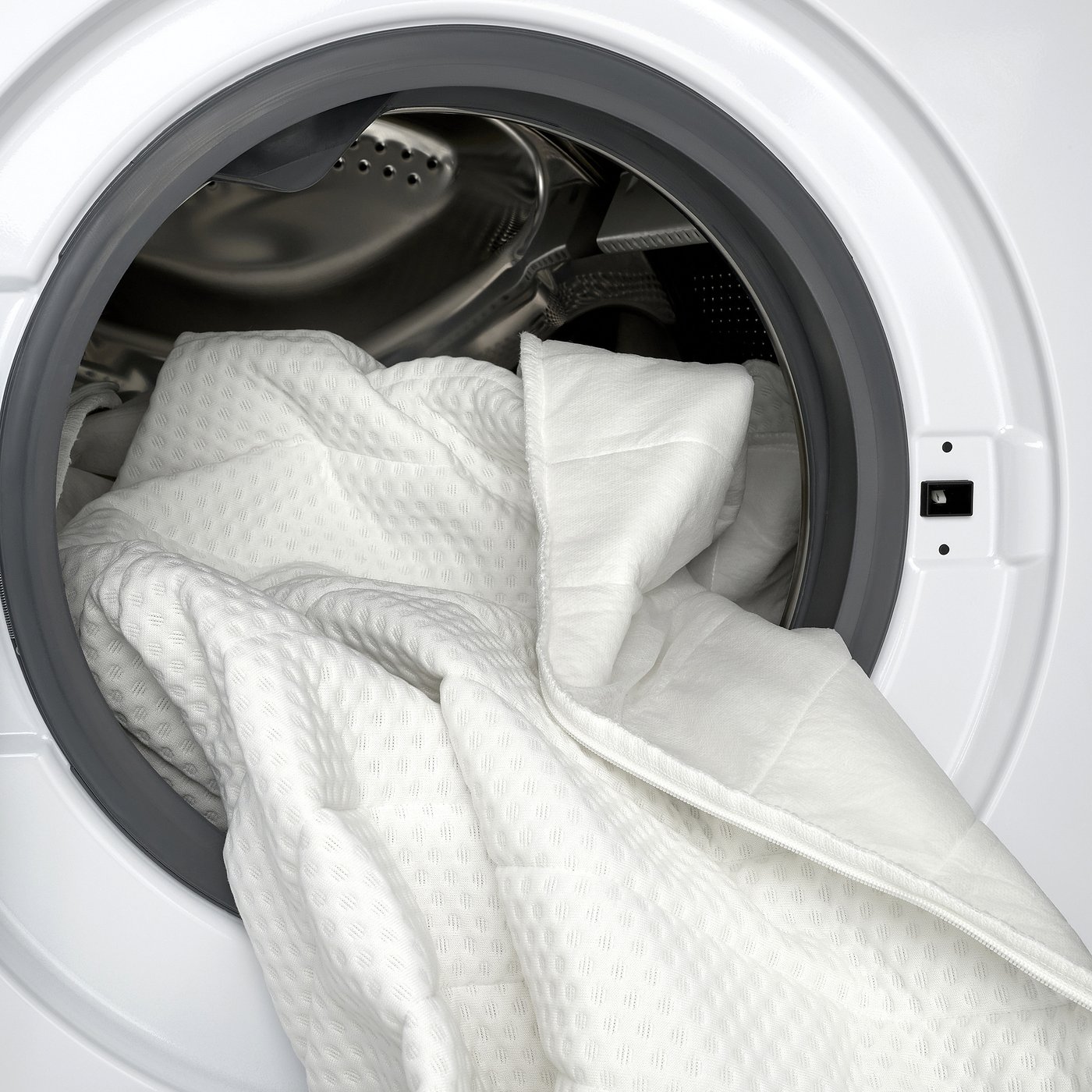 White dryer with mattress pad inside, showcasing machine washable cover.