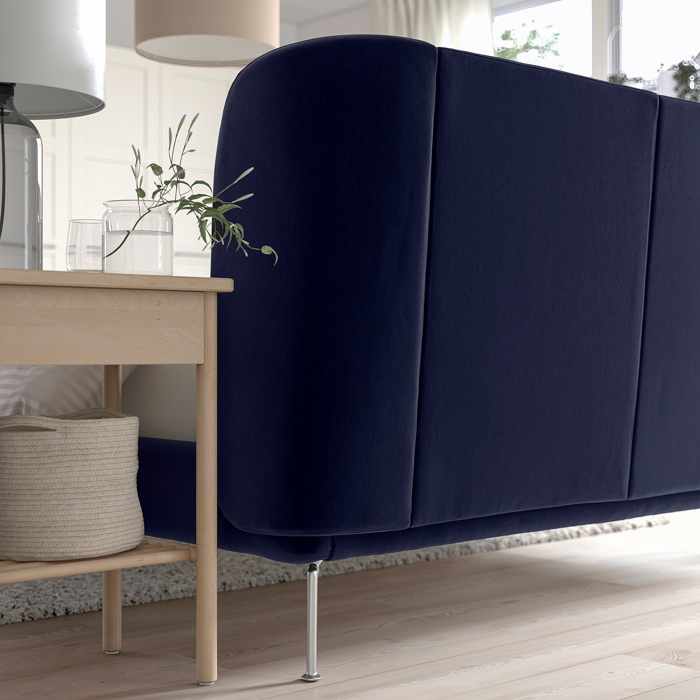 Dark blue upholstered bed with curved headboard, adjustable bed sides, and light wooden legs, perfectly fitting into a cosy room.