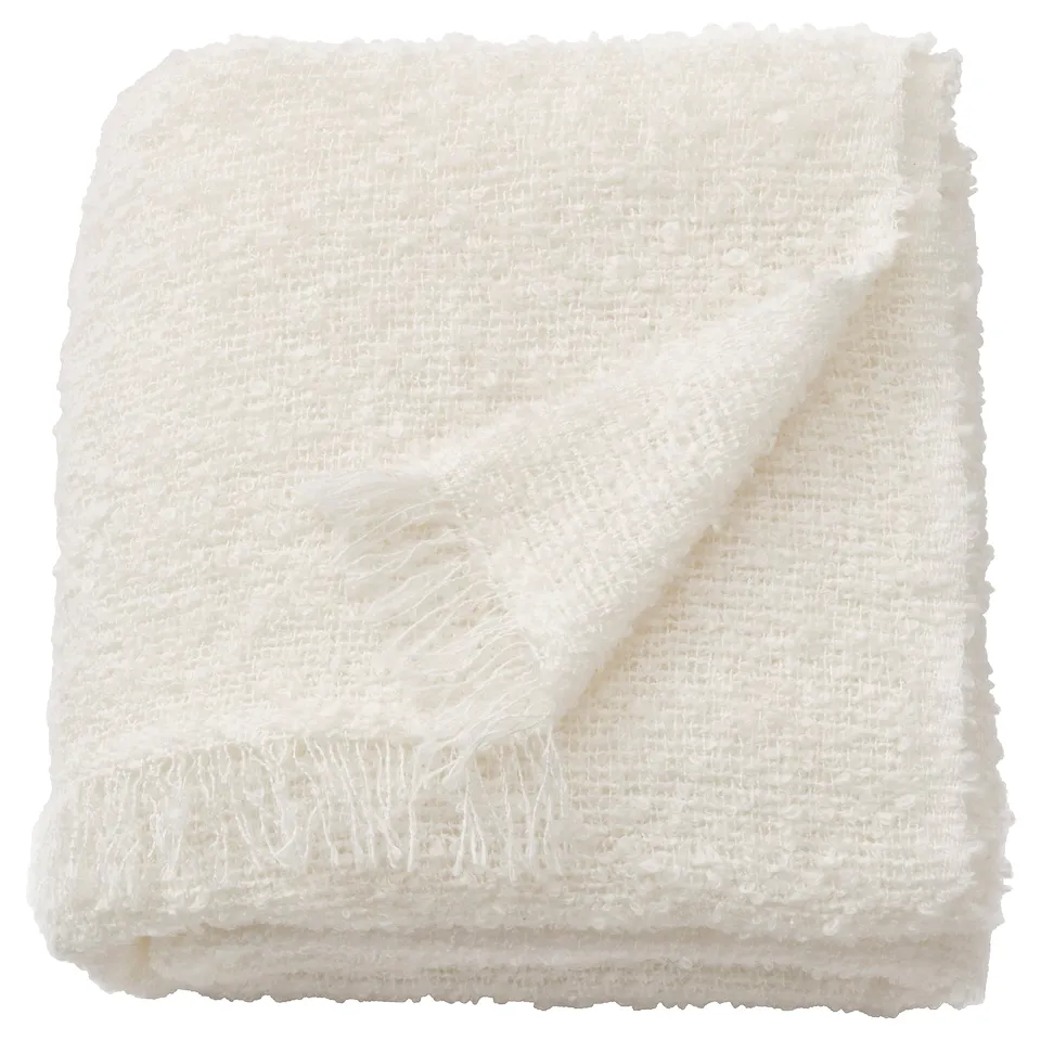 Folded white SANDBRODD throw blanket with fringed edges, soft textured knit.