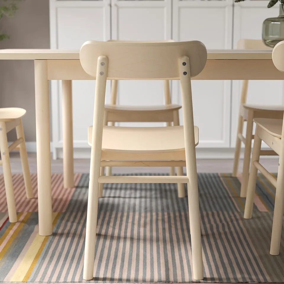Light wooden chairs around a light table. Simple, robust design with visible grain. Suitable for home or public use.
