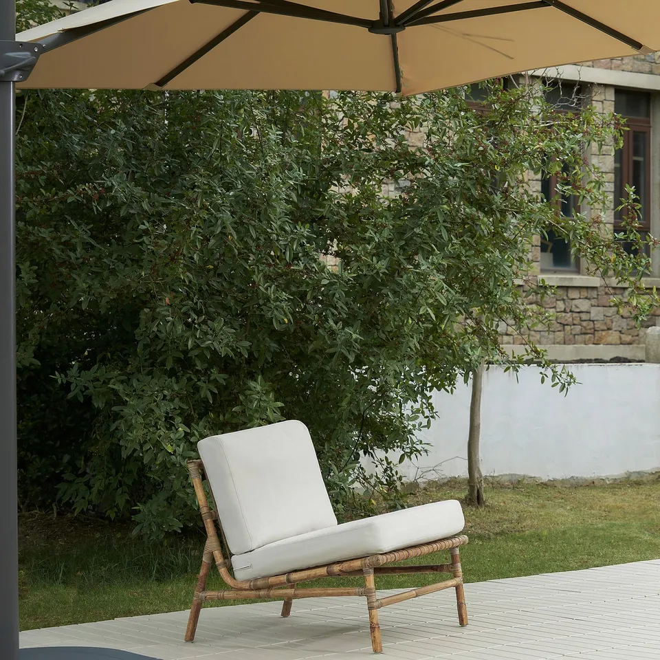 TVARÖ outdoor chair in natural rattan, beige cushion. Lightweight, airy design; suited for patio relaxation.