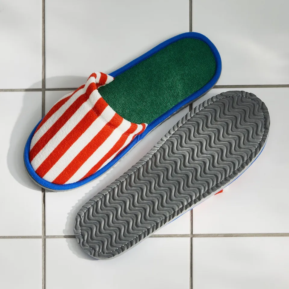 Two colourful striped slippers with non-slip soles on tiled floor.