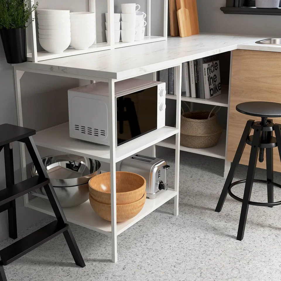 Modern kitchen island with open storage, displaying bowls, toaster, microwave, and books.