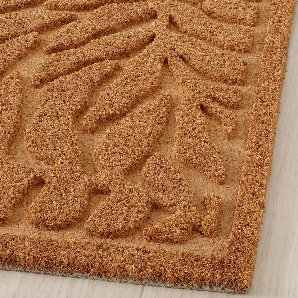 Natural fibre door mat with intricate 3d leaf pattern; durable, stylish, eco-friendly design.