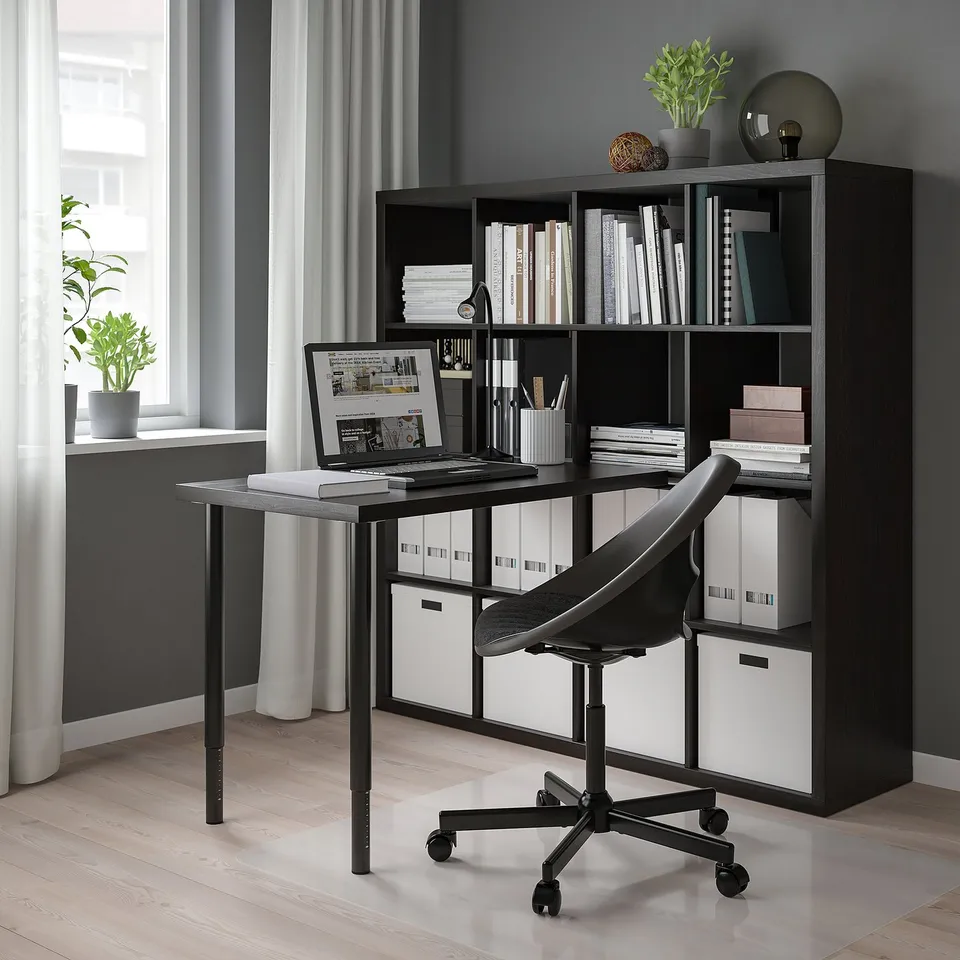 Modern workspace with KALLAX shelving, laptop, and large window.