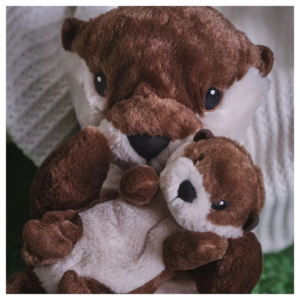 Two plush brown otters, one holding the other, with soft texture and detailed ideal for cuddling.
