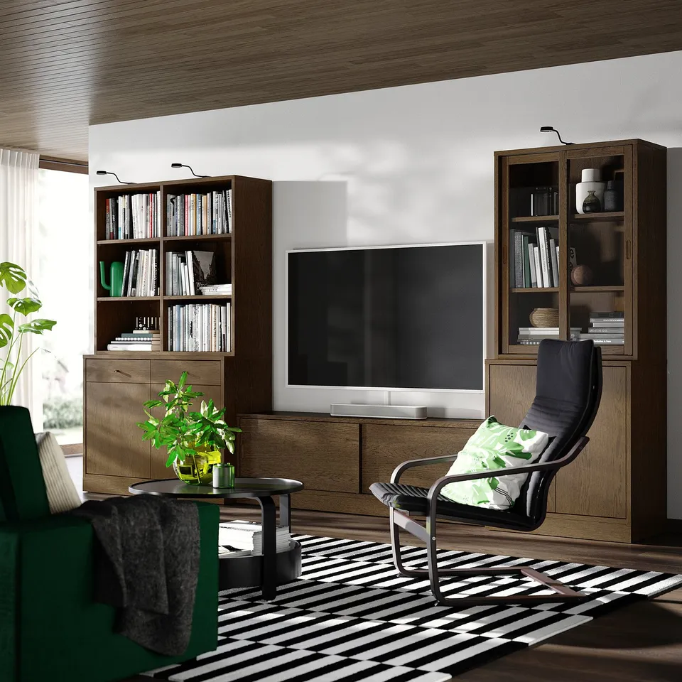 Modern living room with large tv, dark chair, wooden shelves full of books, and a striped rug.