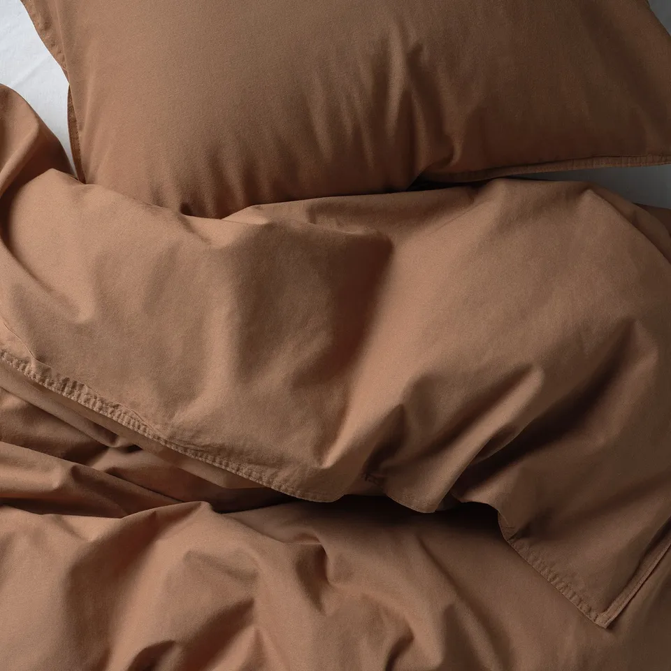 Brown bed sheet, soft and textured, laid casually on mattress.