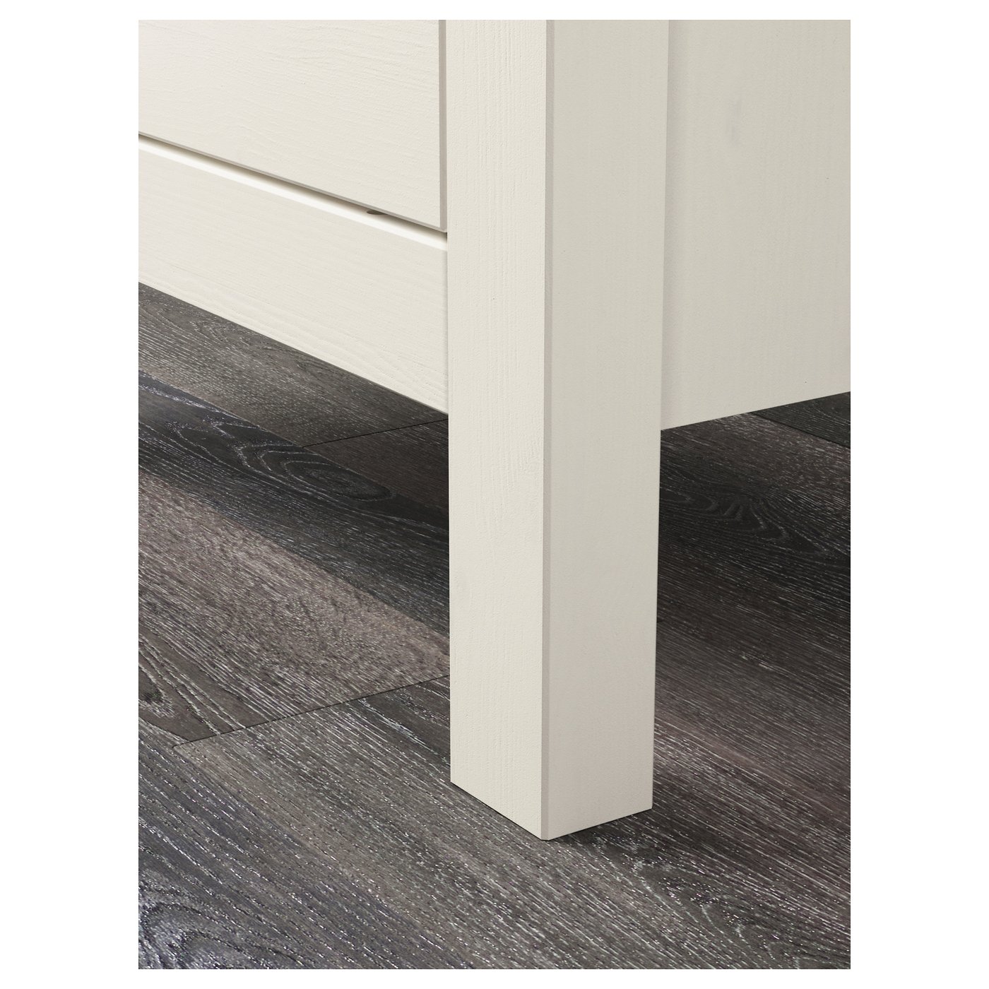 HEMNES furniture leg close-up, white on dark wood.