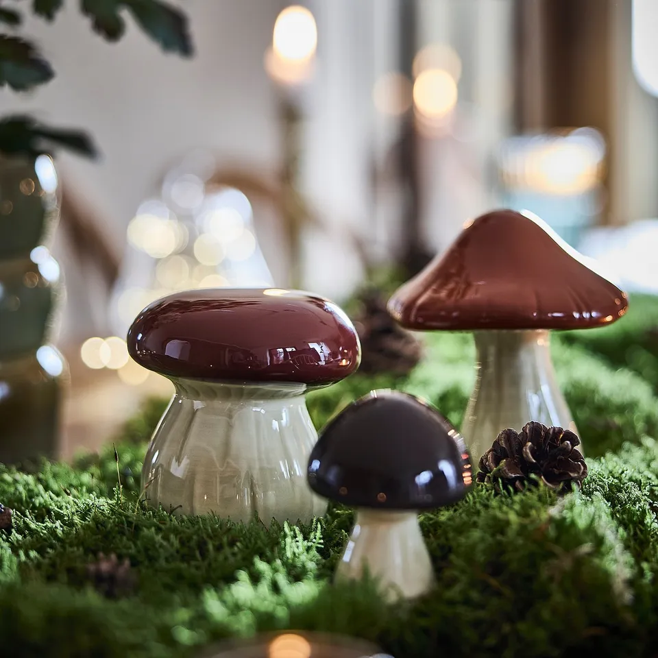 Ceramic mushrooms, HÖSTAGILLE, brown/black, on green moss. Glossy, varied shapes, autumn decor.