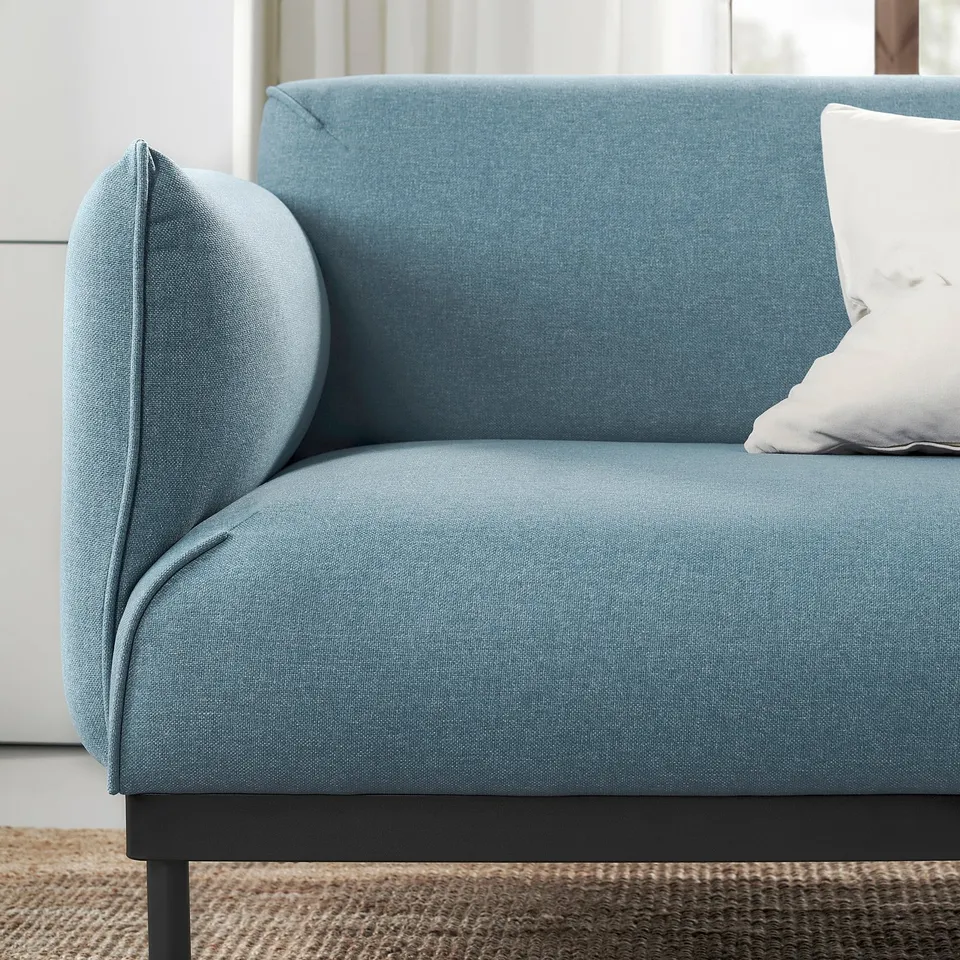 A blue fabric sofa with a pillow, showcasing modern design.