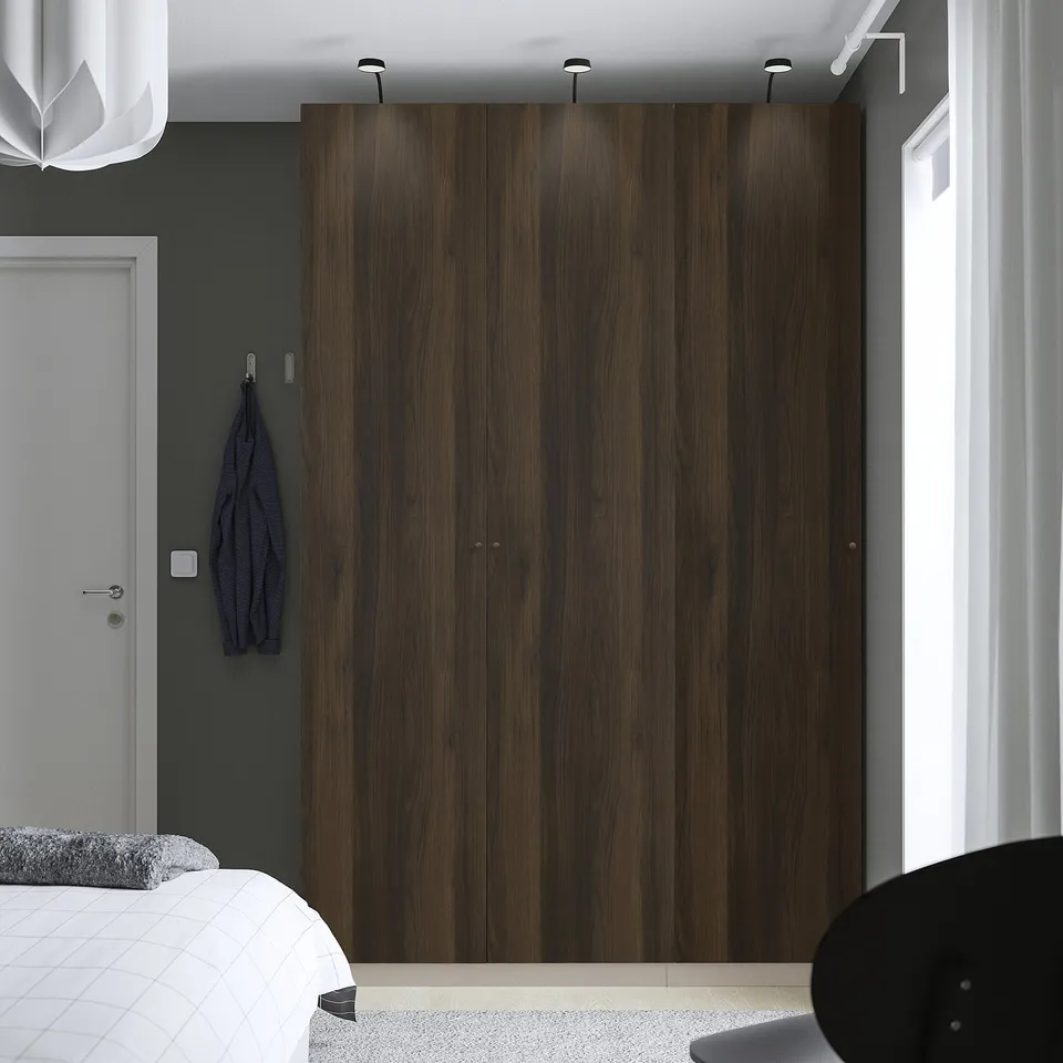 Modern bedroom with large dark wood wardrobe featuring sleek design. Elegant and spacious, complementing the minimalistic decor.