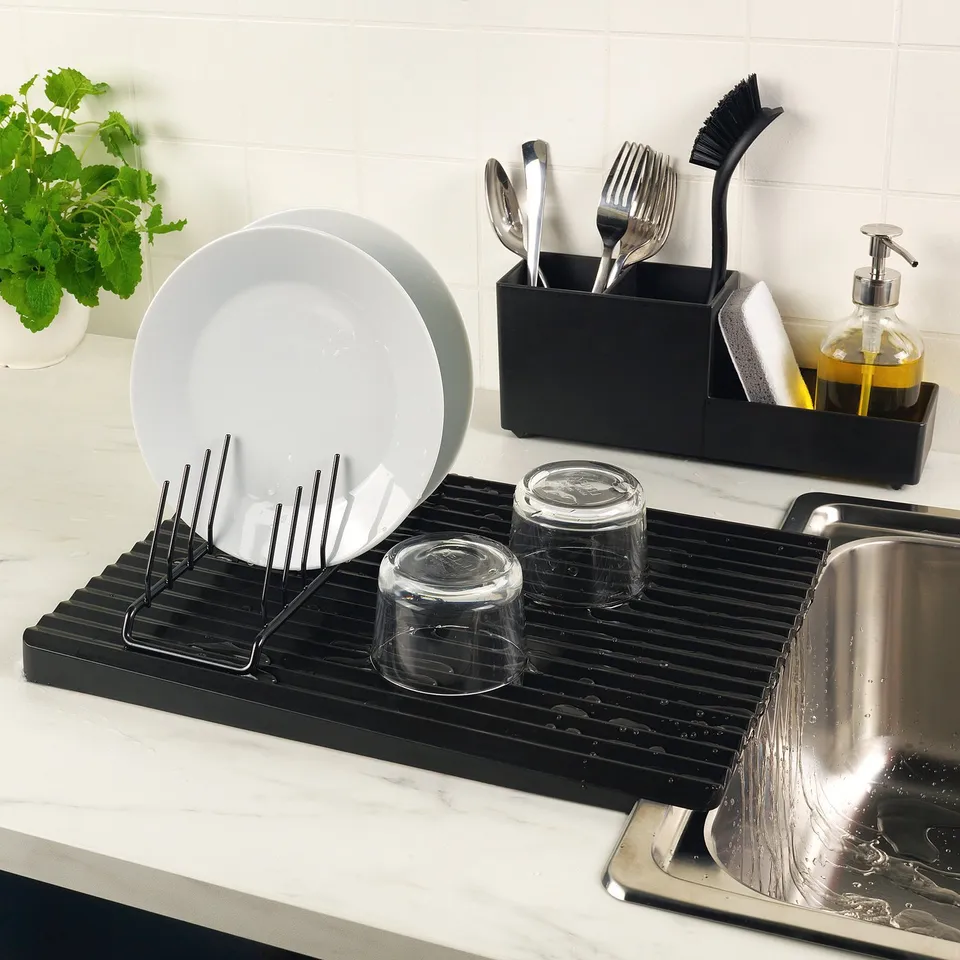 Black dish drying rack on counter with white plate, two glass cups, and cutlery organiser.