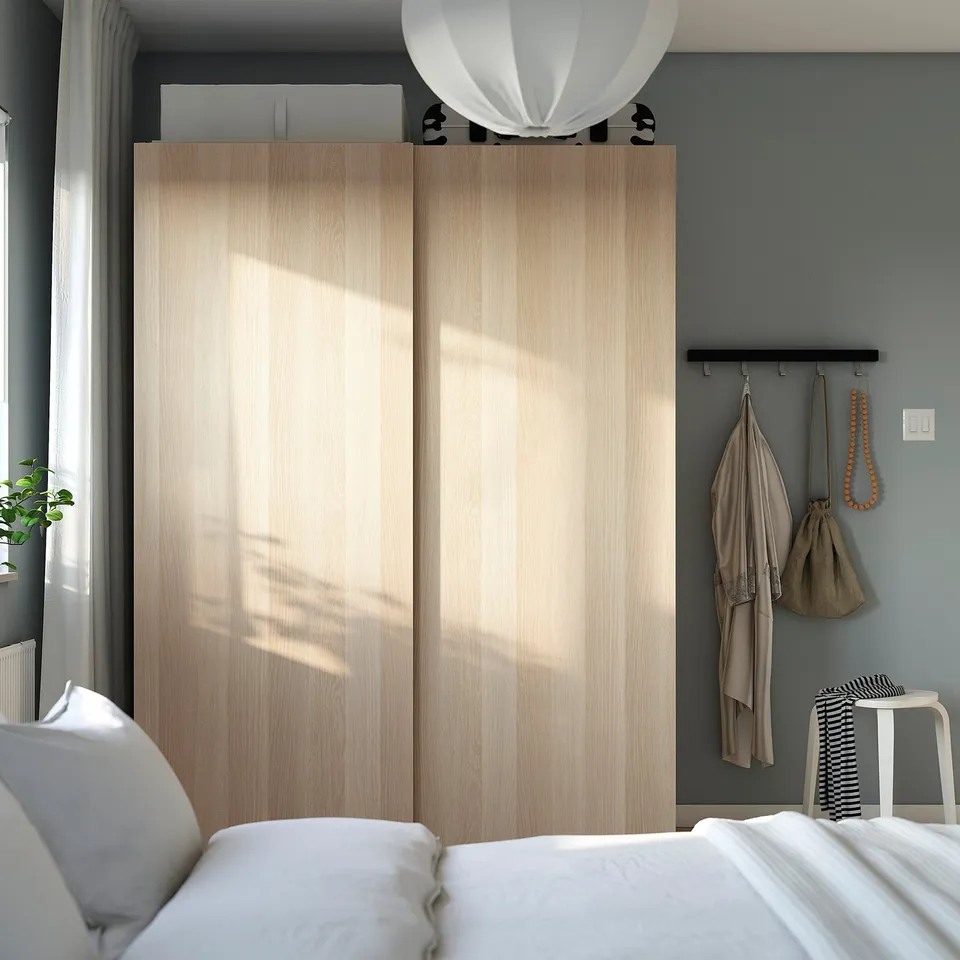 Bedroom with PAX wardrobe, bed, pendant light, and plants.