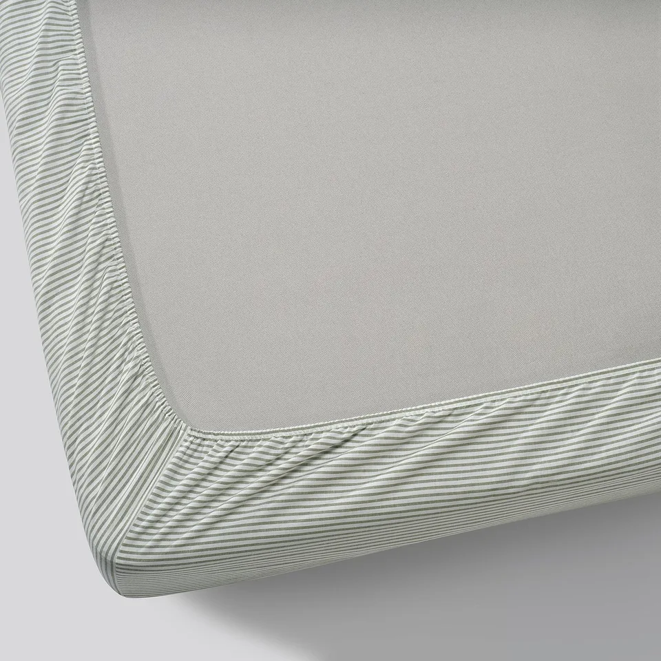 Close-up of a grey SOLFIBBLA fitted sheet, showcasing its elastic edges and textured fabric, made from 100% recycled cotton.