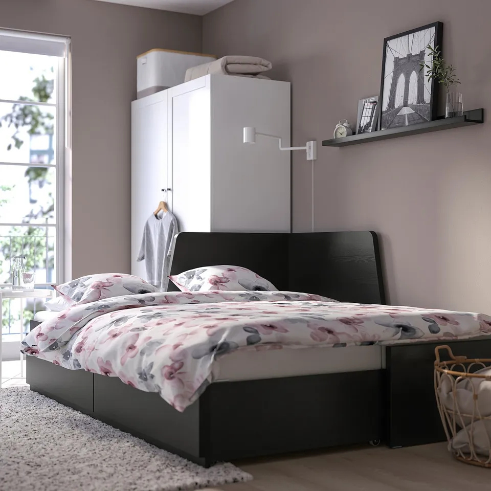 Bedroom with FLEKKE day-bed with floral bedding, white wardrobe, wall shelf, and large drawers for storage.