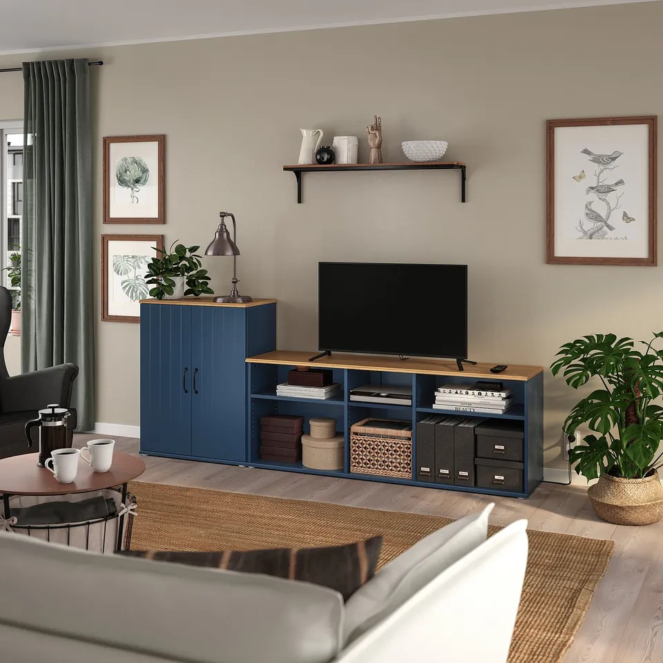 Modern living room with blue SKRUVBY tv unit, surrounded by cosy furniture and plants.