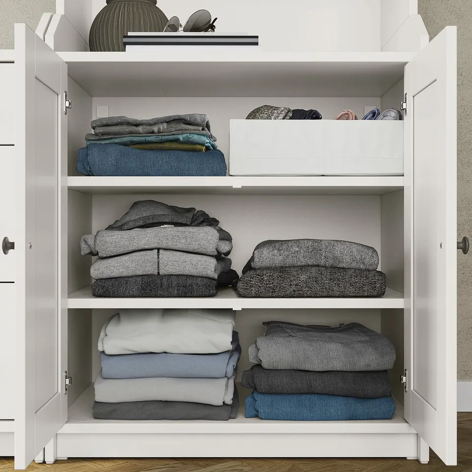 HAUGA white wardrobe with folded clothes, boxes, decor on shelves.