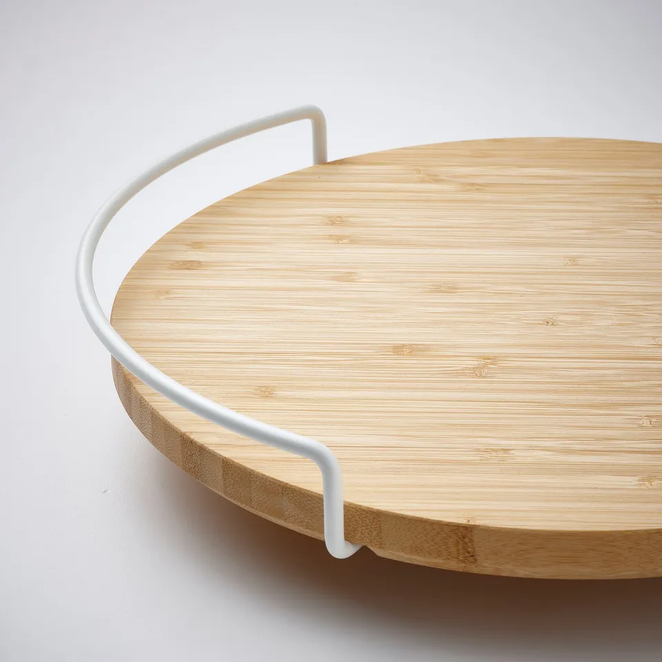 A round bamboo tray with white metal handle, ideal for kitchen use.