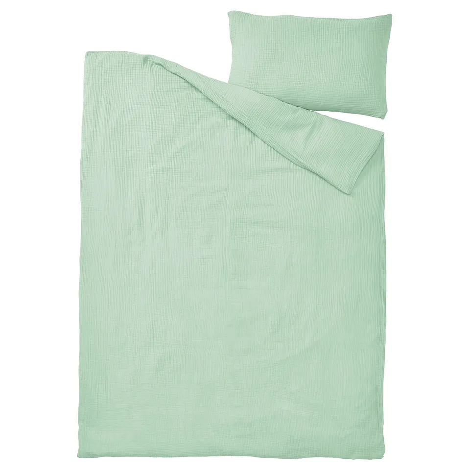 A light green SCHERSMIN duvet cover and pillowcase in soft, airy muslin fabric made from 100% organic cotton.