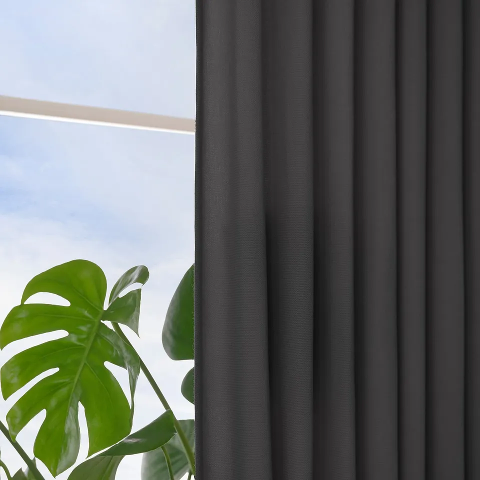 Large window with dark grey GINSTMOTT curtains, providing privacy and letting in diffused light, with green plant in foreground.