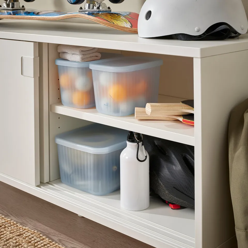 Clear storage boxes in a shelf organise small items in a bathroom.