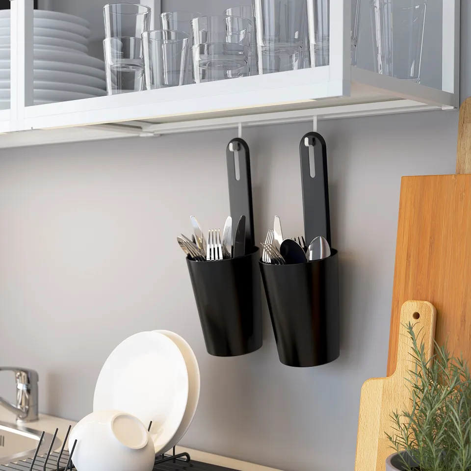 Kitchen storage: utensils in hanging containers, glassware in cabinet, cutting board and plant displayed, efficient organisation.