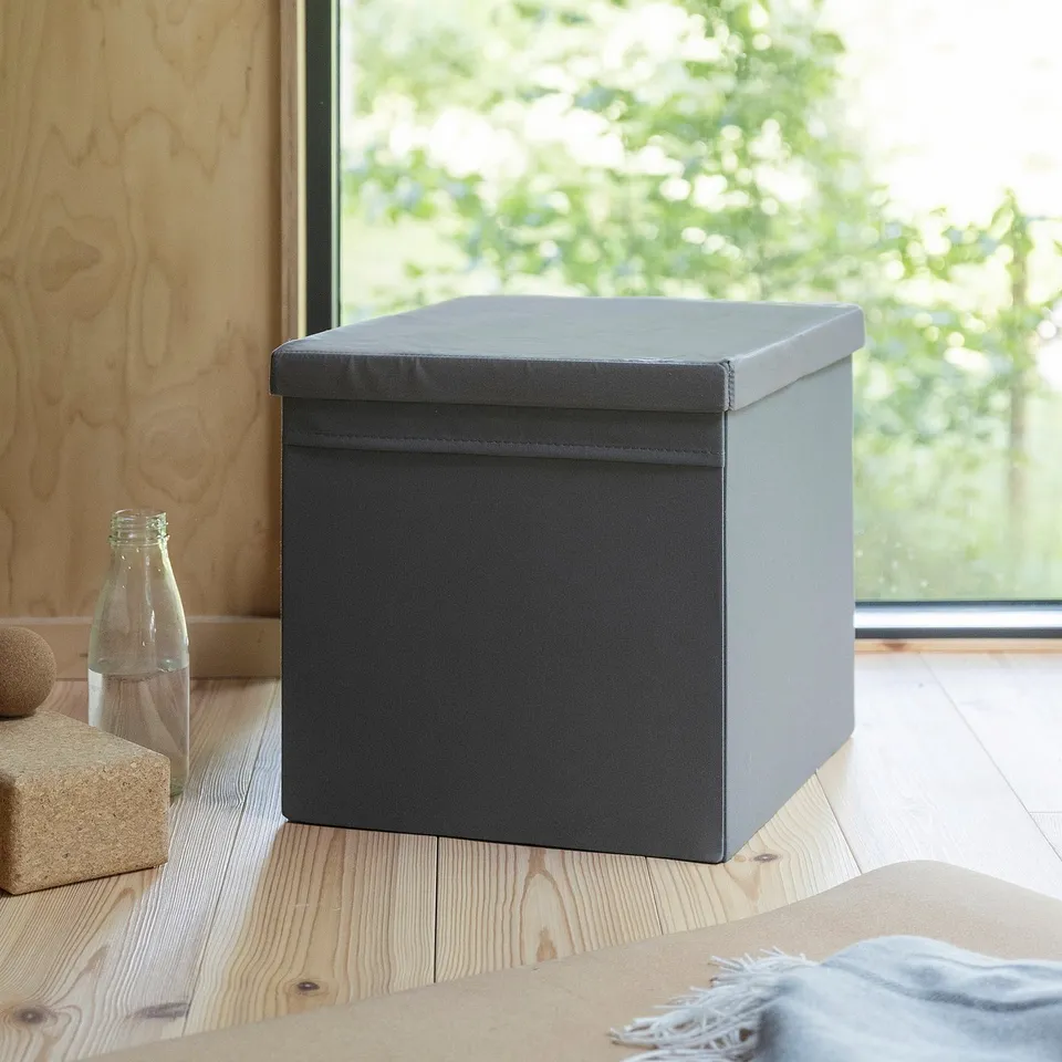 DRÖNA grey fabric storage box with lid on wooden floor, near glass bottle and cork pieces, fits kallax shelf.