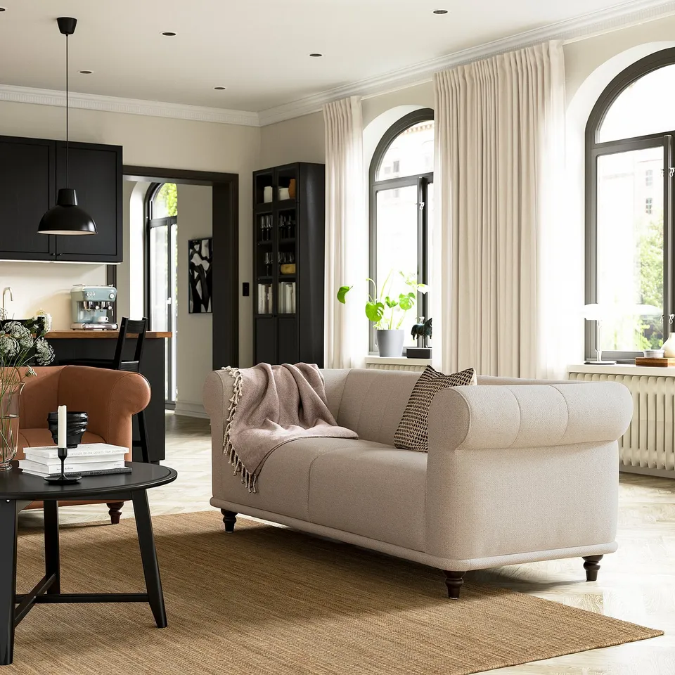 Modern living room with beige VISKAFORS sofa, brown chair, black coffee table, and large arched windows with sheer curtains.
