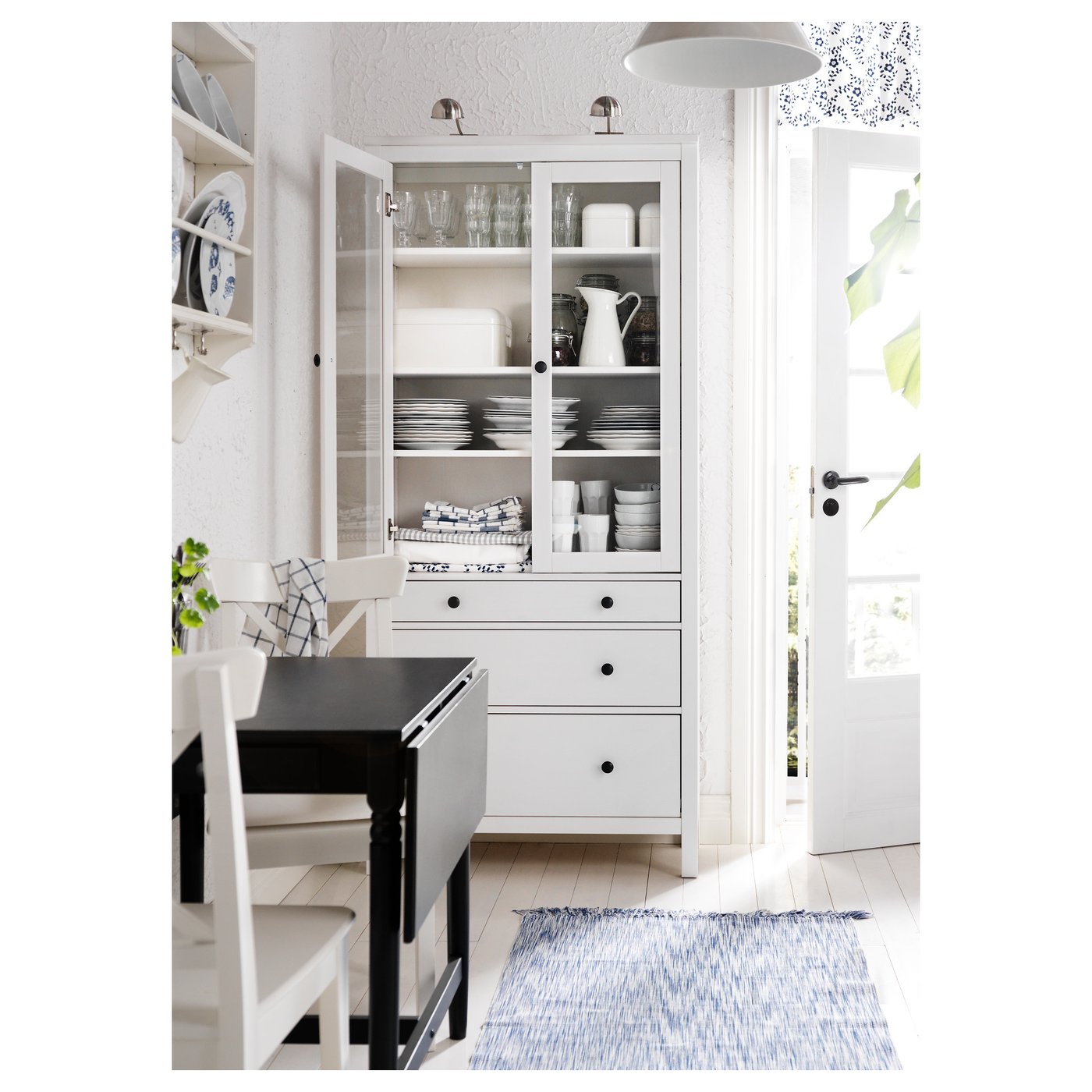 Modern white kitchen featuring HEMNES glass-door cabinet and black dining table.