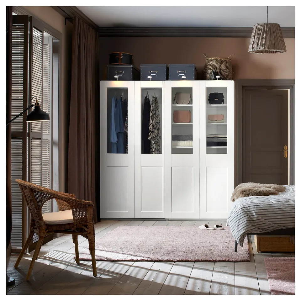 Modern bedroom with PAX wardrobe, wicker chair, rug, and pendant lamp.