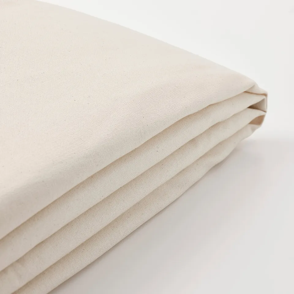 Folded cream-colored cotton fabric; smooth, high-quality texture visible.