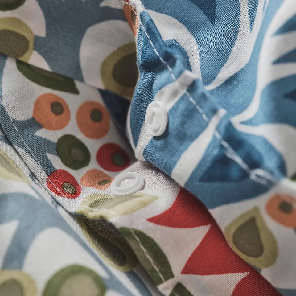 Close-up of SÄTERVIDE duvet, showing button-like fasteners securing the cover. Bright colours and intricate patterns visible.