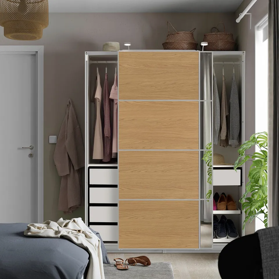 Modern bedroom with light wood PAX wardrobe, sliding doors, mirrored section, clothes & drawers, next to bed.