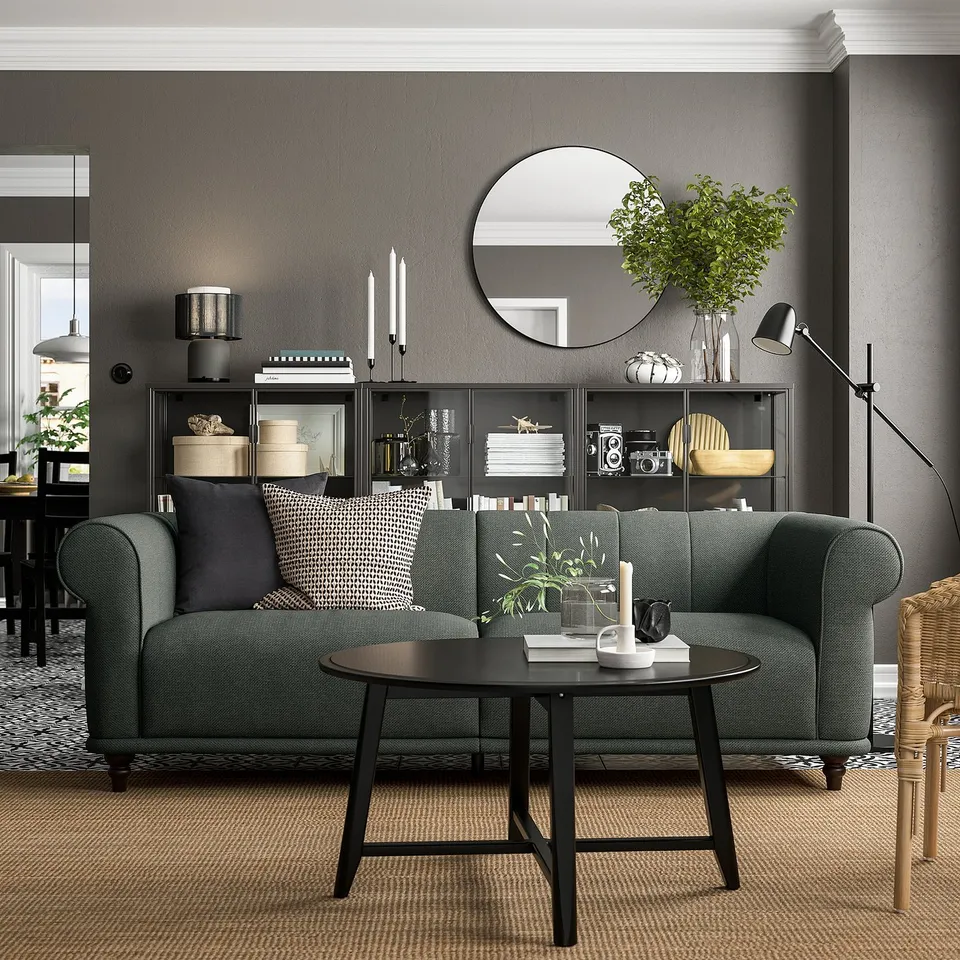 Modern living room with green VISKAFORS sofa, dark coffee table, black side cabinet, and decorative plants.