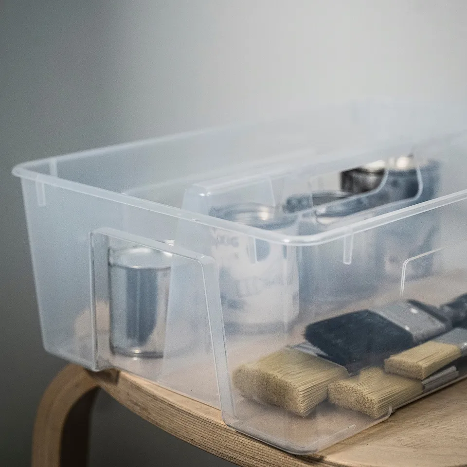 Clear, portable organiser with handle holds small items.