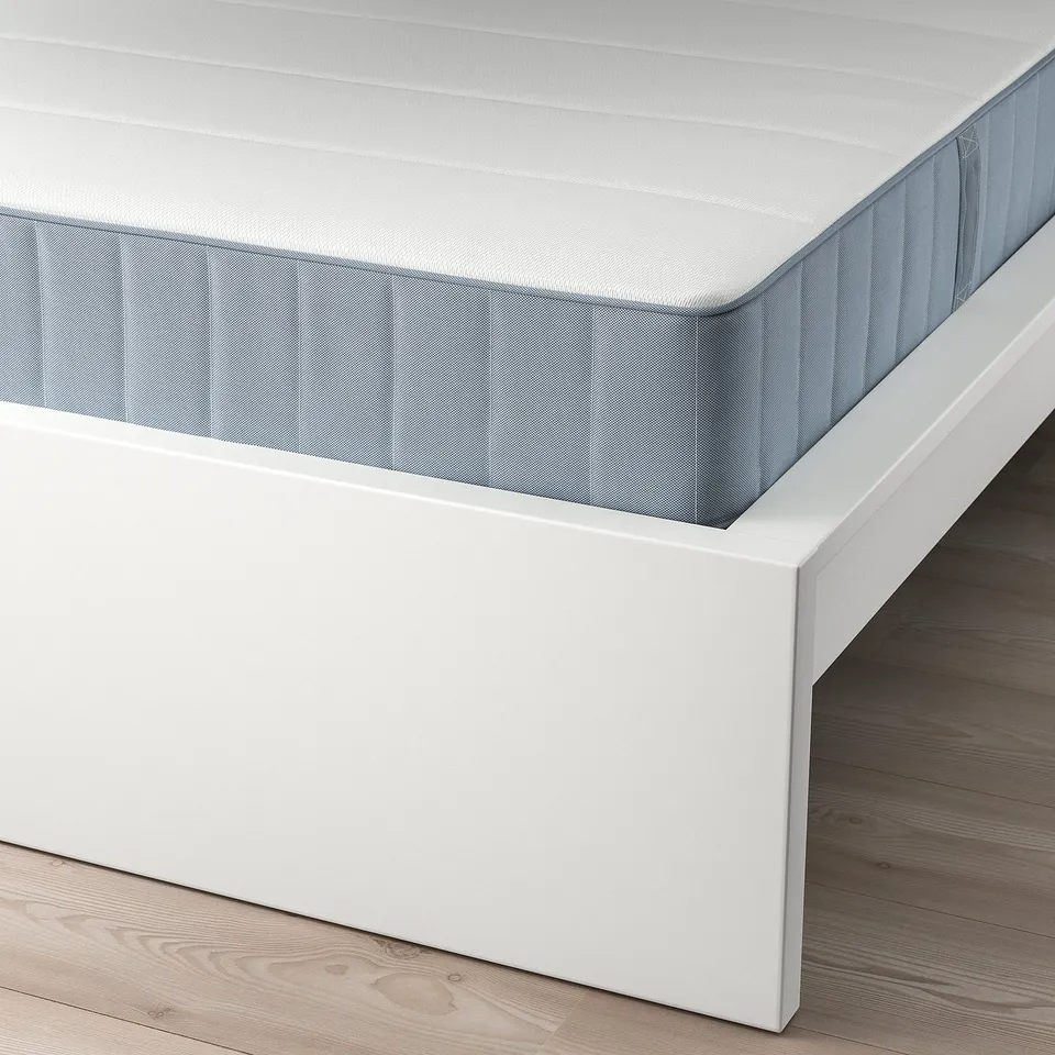 White MALM bed frame with adjustable slats supporting mattress, shown on wooden floor.