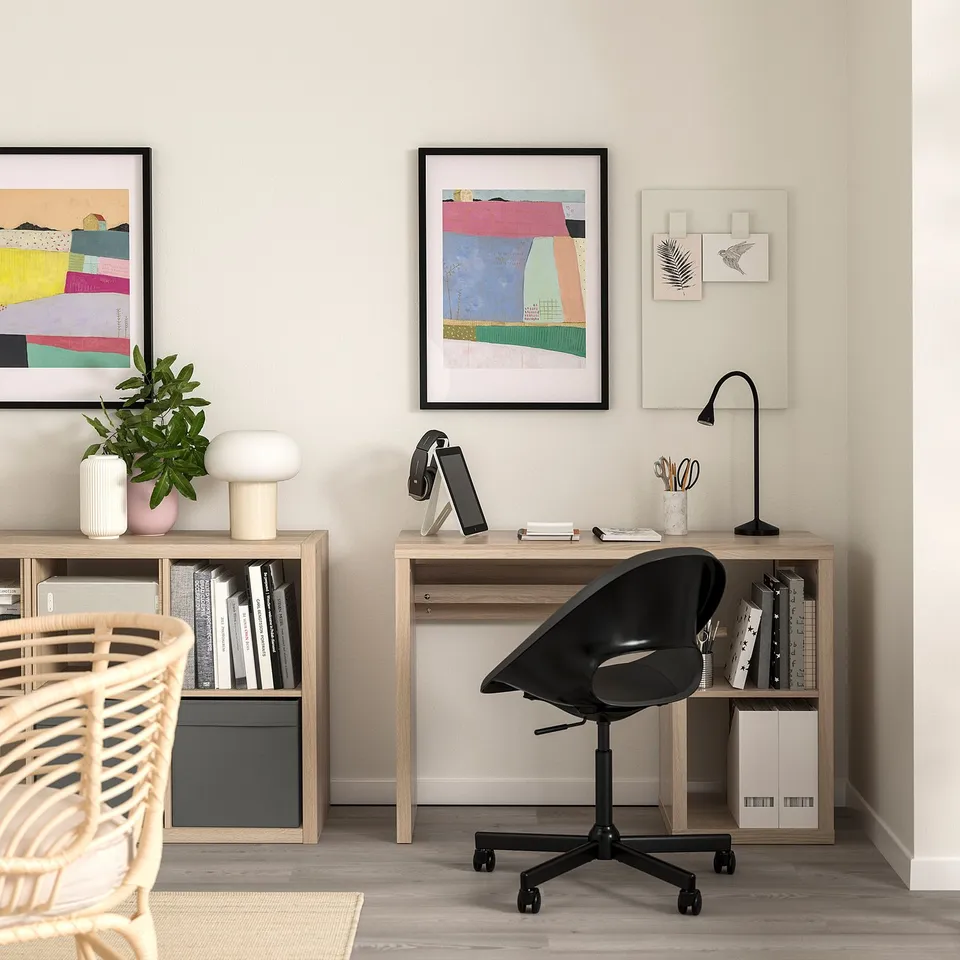 Modern home office with KALLAX desk, ergonomic chair, & abstract art.